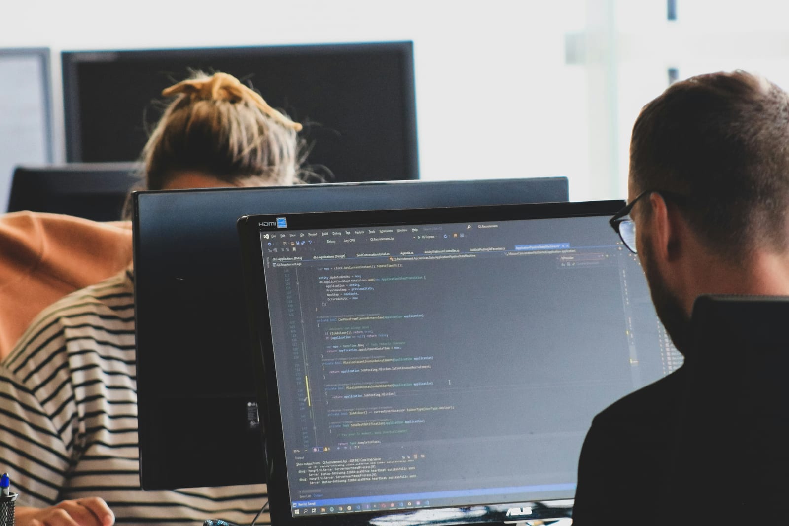 Zwei Entwickler arbeiten am Bildschirm an Quellcode – förderfähige Softwareentwicklung